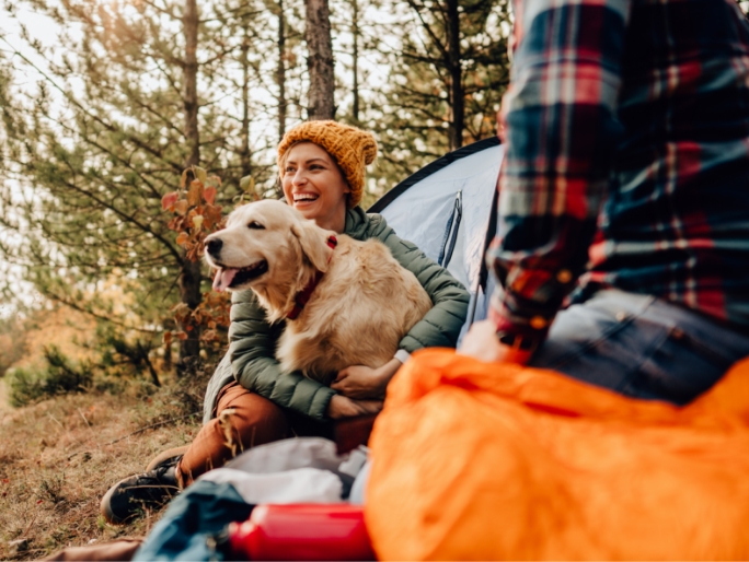 A young couple and their dog camping in the woods on a beautiful autumn day
